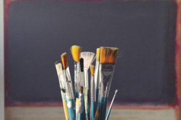 paint brushes on a table with a board in the background